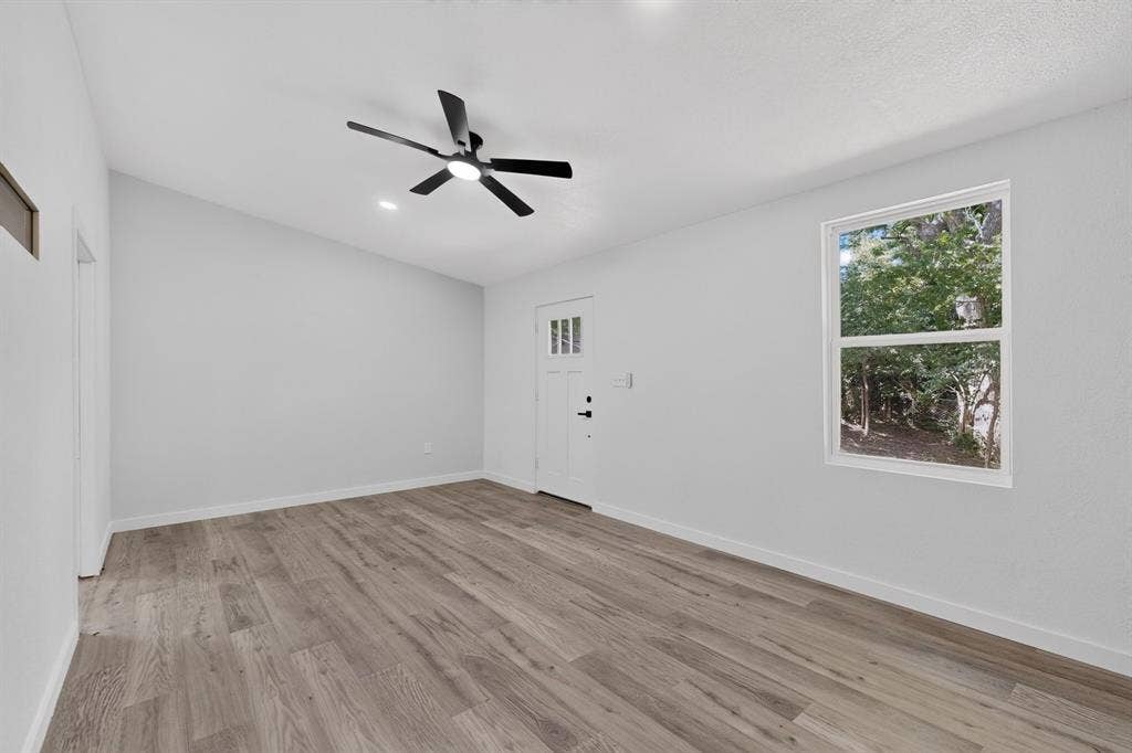 550 Glen Oaks Boulevard, Dallas, TX 75232 Room featuring wood-finish flooring, a matte black multi-blade ceiling fan with integrated light, a single-hung window, and a door with three-lite glazing