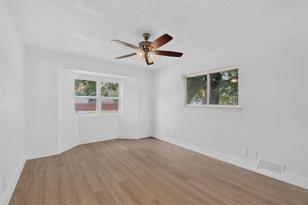 550 Glen Oaks Boulevard, Dallas, TX 75232 Room featuring wood-finish flooring, a bay window, a dual-pane window, and a multi-blade ceiling fan with integrated lighting