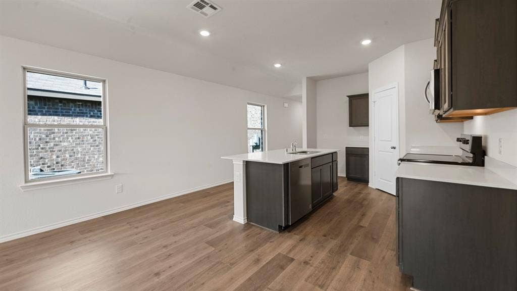 5731 Sunshine Lane, Crandall, TX 75114 Open-concept kitchen and living area featuring wood-finish flooring, recessed lighting, a kitchen island with sink, and dark gray cabinetry