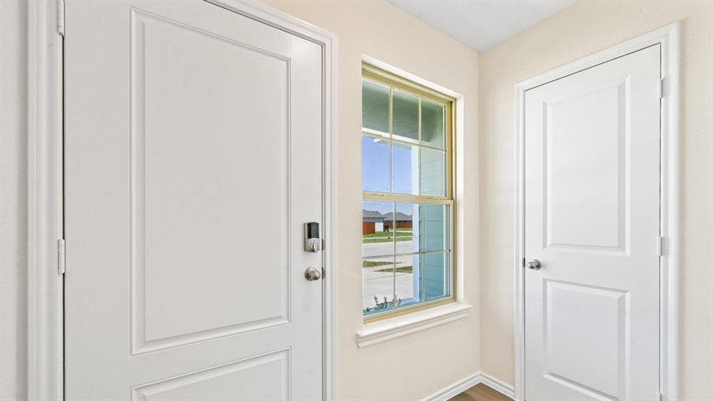 5739 Sunshine Lane, Crandall, TX 75114 Entryway featuring a white paneled door with smart lock hardware, a double-hung window with a golden-hued frame, and light-toned walls
