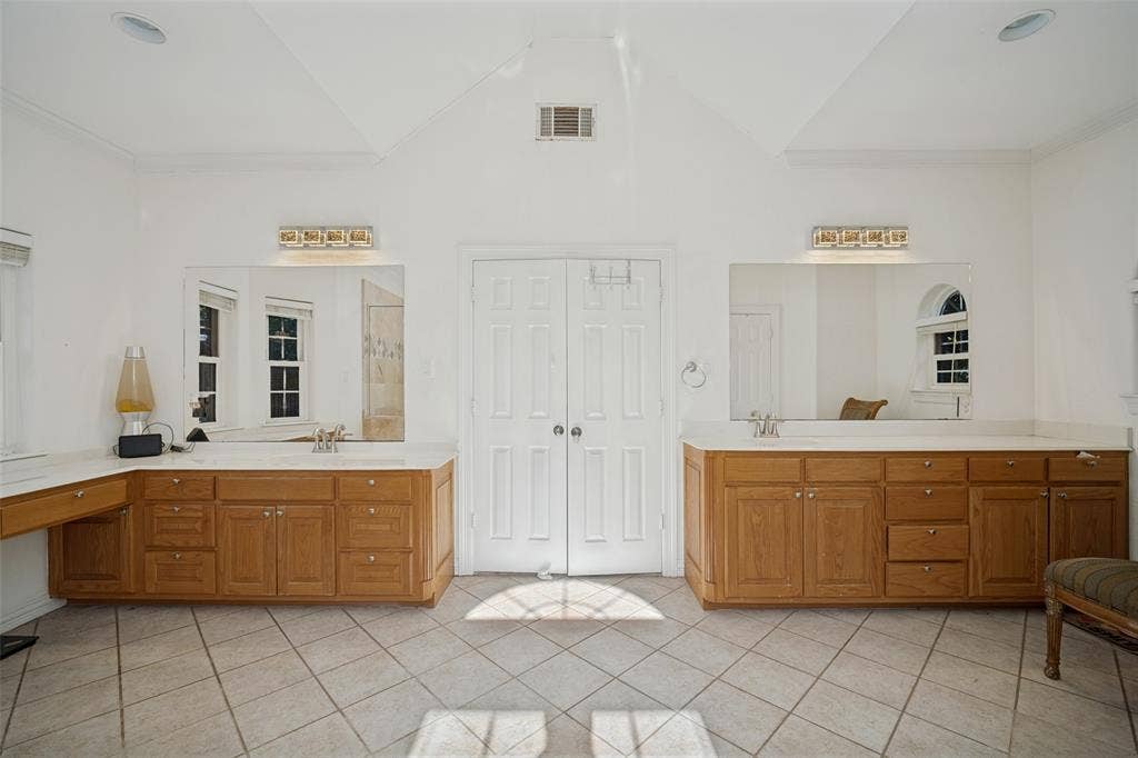 1957 E Fm 550, Rockwall, TX 75032 Dual vanities with wood cabinetry and light-toned solid surface countertops, vaulted ceiling, large wall-mounted mirrors, and diagonal-set tile flooring