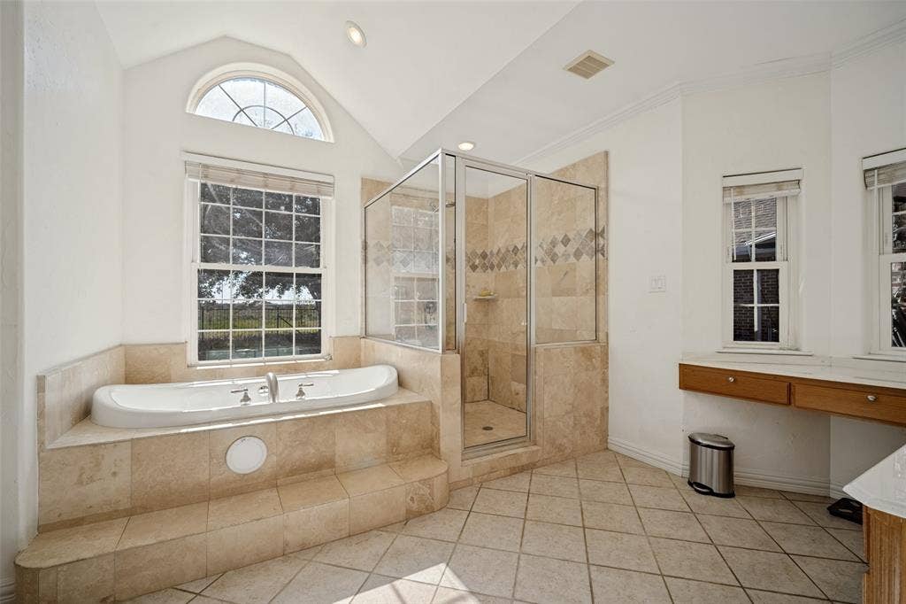 1957 E Fm 550, Rockwall, TX 75032 Soaking tub with stone-tile surround, glass-enclosed shower, vaulted ceiling, arched window, and dual built-in vanities.