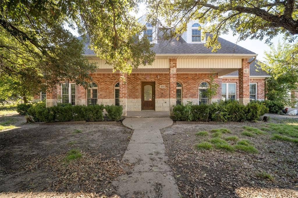 1957 E Fm 550, Rockwall, TX 75032 Multi-story brick and stone facade featuring arched window frames, triple dormer windows, and a covered entryway