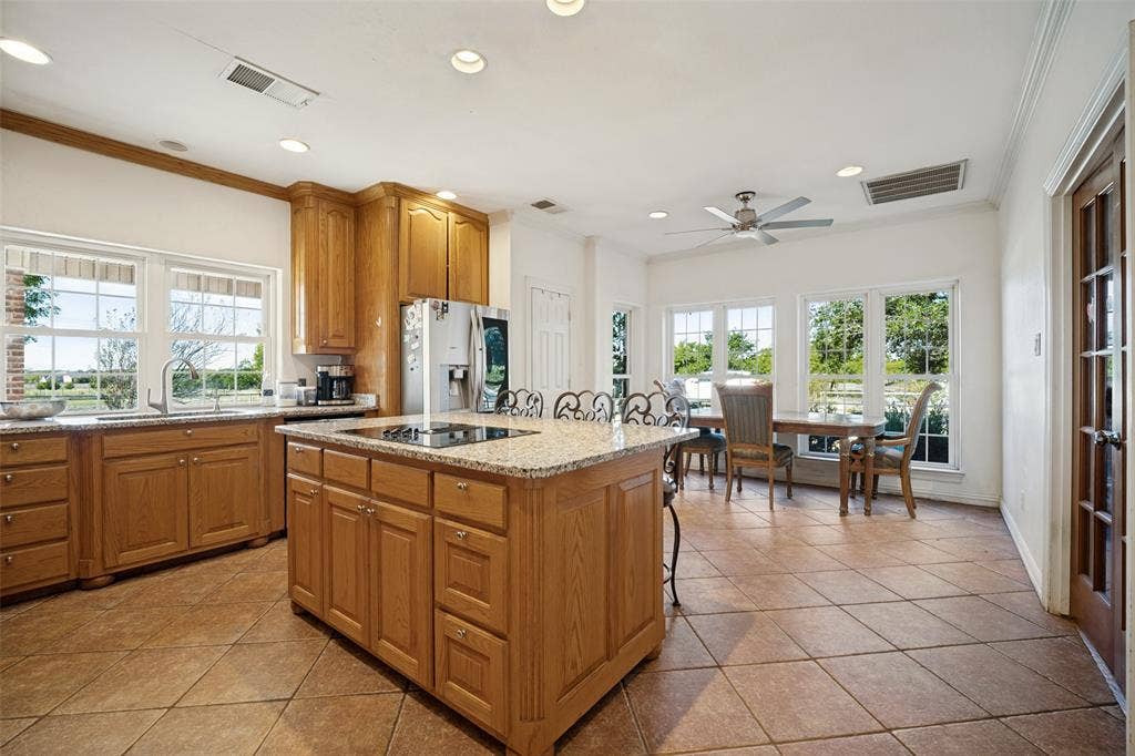 1957 E Fm 550, Rockwall, TX 75032 Kitchen featuring wood cabinetry, stone countertops, a center island with a built-in cooktop, tiled flooring, and recessed lighting