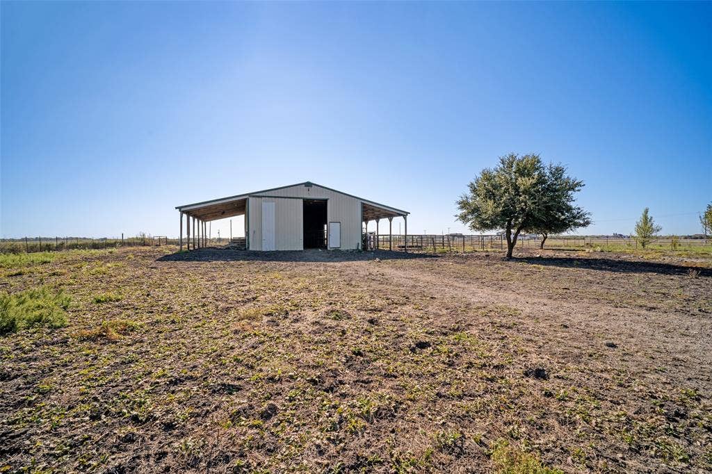 1957 E Fm 550, Rockwall, TX 75032 Metal-clad barn featuring covered side overhangs, a central drive-through bay, exterior holding areas and surrounding acreage.