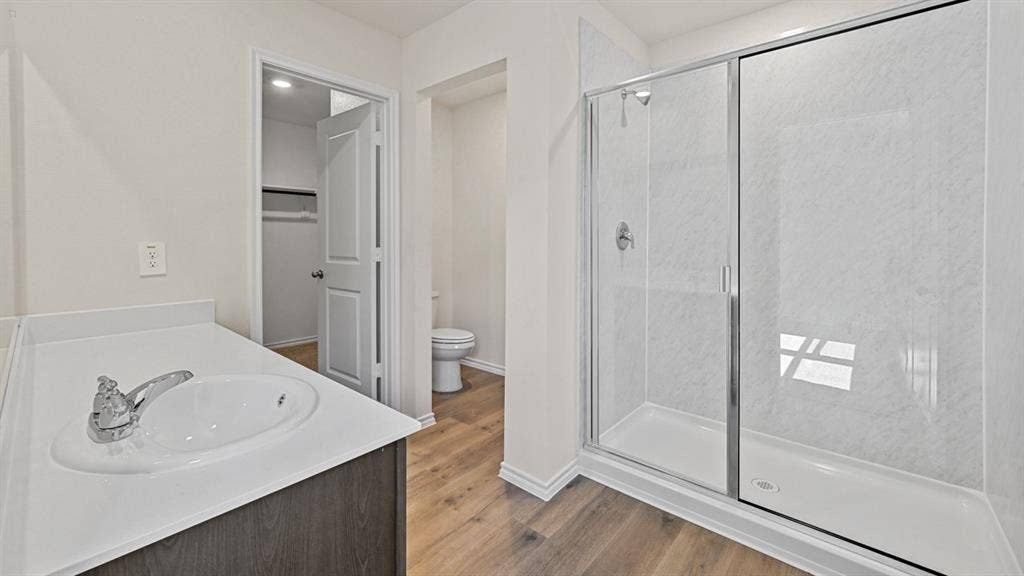 5743 Sunshine Lane, Crandall, TX 75114 Walk-in shower with a glass enclosure, single vanity with an integrated sink, wood-finish flooring, and a built-in closet with shelving