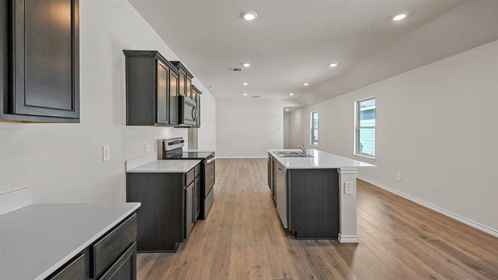 5743 Sunshine Lane, Crandall, TX 75114 Kitchen featuring dark wood cabinetry, light-toned countertops, stainless steel appliances, and a central island with an undermount sink