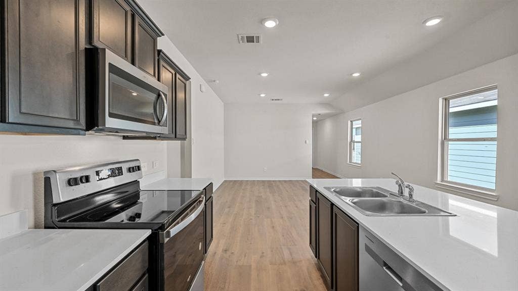 5743 Sunshine Lane, Crandall, TX 75114 Kitchen featuring dark wood-finish cabinetry, stainless steel appliances, white countertops, a double basin sink, and recessed lighting