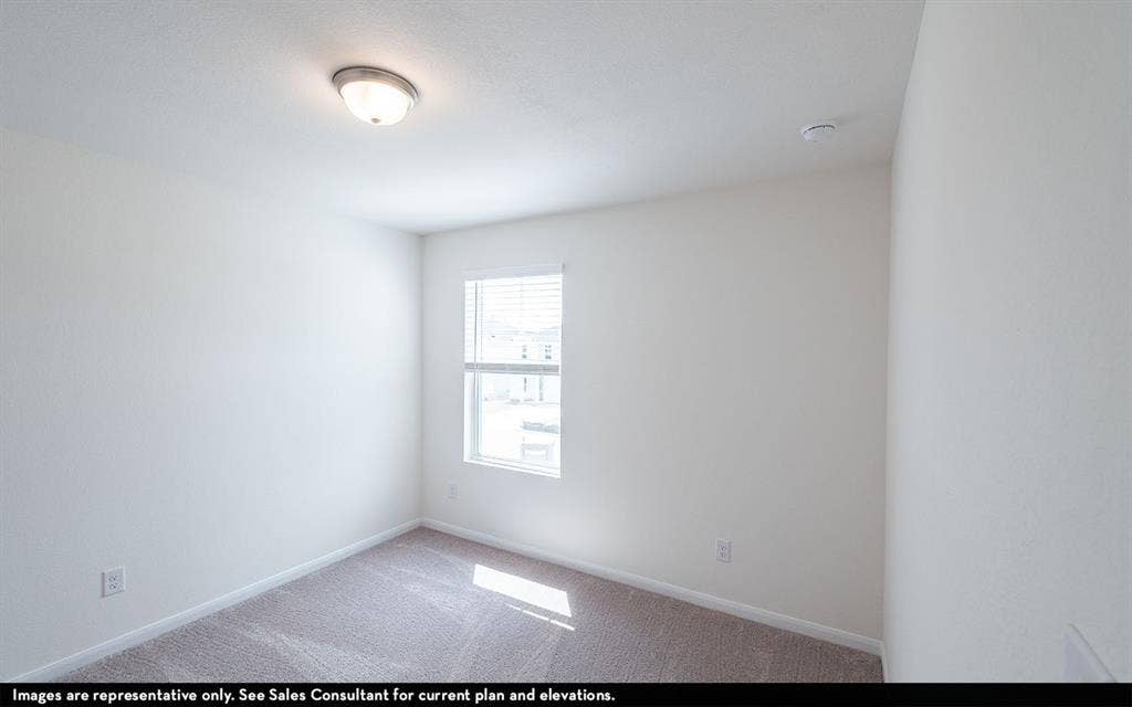 Neutral-toned interior space featuring plush carpeting, a single-pane window with white blinds, and a flush-mount dome light fixture