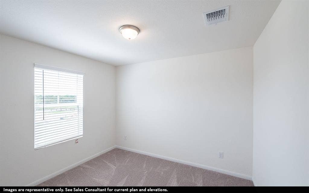 Neutral-toned interior space featuring light-colored wall paint, carpeted flooring, a single-window configuration with horizontal blinds, and a flush-mount ceiling light fixture