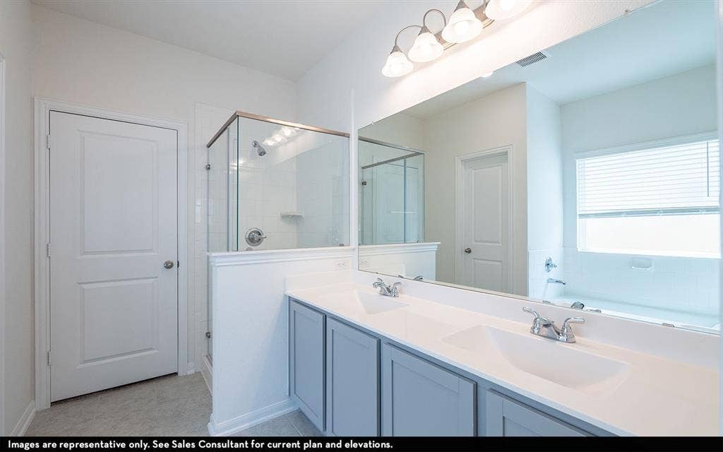 Double vanity with a solid-surface countertop and integrated dual sinks, full-width wall mirror, glass-enclosed shower with tiled surround, and Shaker-style cabinetry
