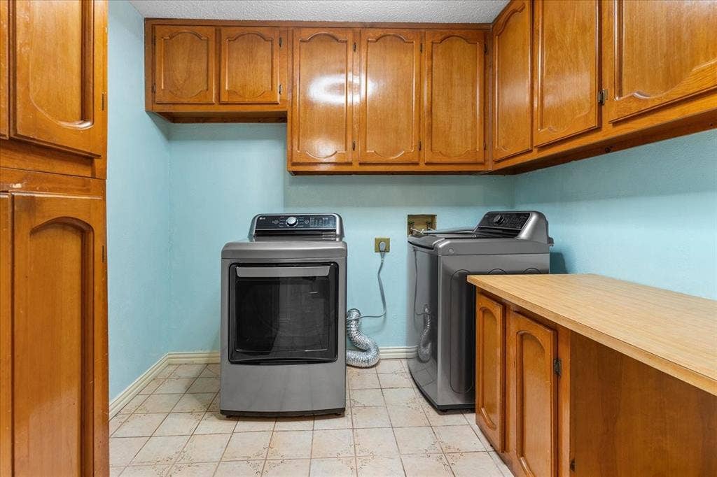 2702 Pebble Beach Drive, Lancaster, TX 75134 Utility room featuring wood-finish cabinetry, ample overhead storage, built-in counter space, and tiled flooring