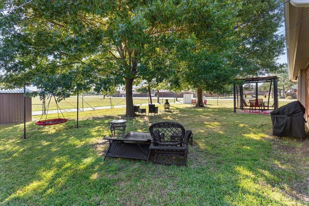 2702 Pebble Beach Drive, Lancaster, TX 75134 Expansive backyard featuring mature shade trees, a metal storage shed, and a metal-frame pergola
