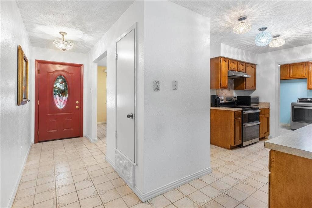 2702 Pebble Beach Drive, Lancaster, TX 75134 Entryway featuring a red paneled door with an oval glass insert, tile flooring, built-in storage closet, and decorative globe-style light fixtures