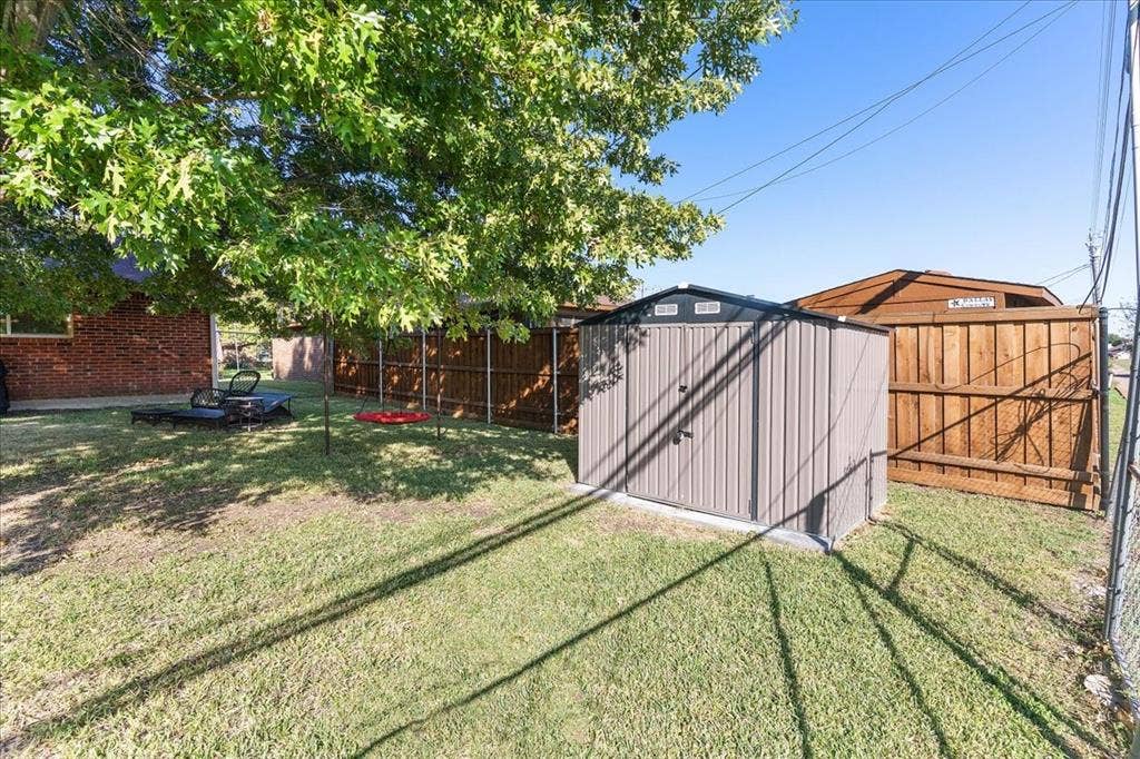 2702 Pebble Beach Drive, Lancaster, TX 75134 Backyard space featuring a metallic storage shed, privacy fencing, and mature tree canopy