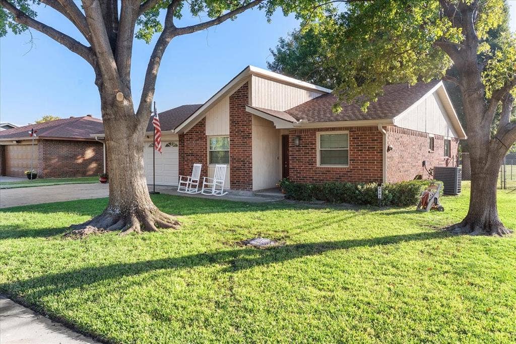 2702 Pebble Beach Drive, Lancaster, TX 75134 Single-story exterior featuring a brick and panel facade, attached garage, composition shingle roof, and mature trees