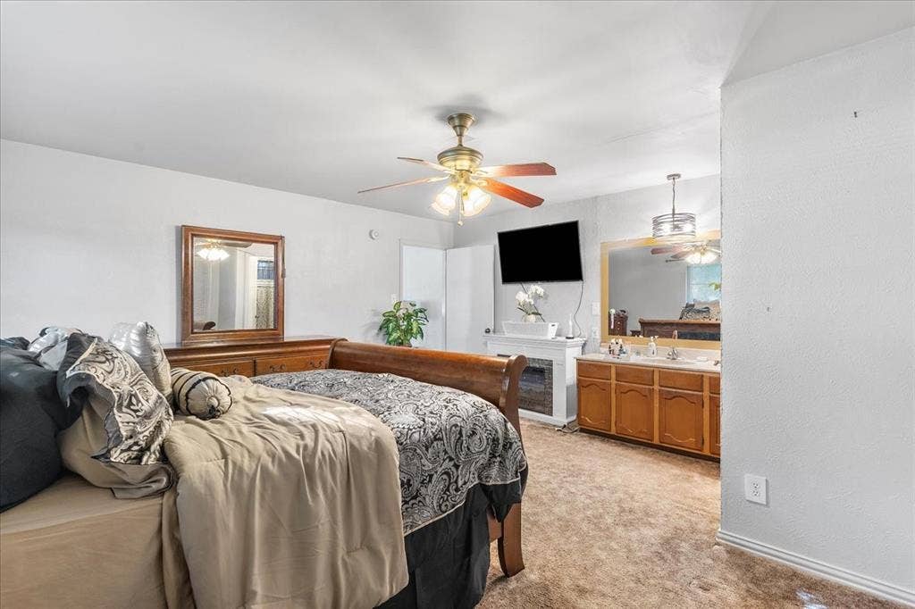 2702 Pebble Beach Drive, Lancaster, TX 75134 Bedroom featuring a multi-light ceiling fan, integrated electric fireplace, and built-in vanity cabinet with a large framed mirror and dual-light fixture