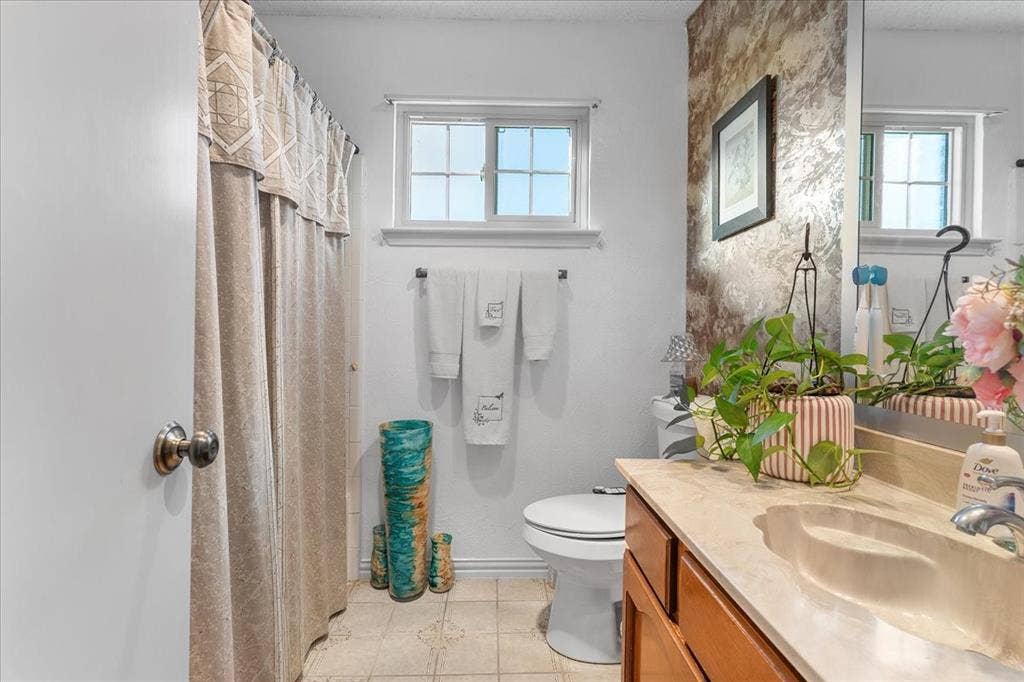 2702 Pebble Beach Drive, Lancaster, TX 75134 Bathroom featuring a vanity with a light-toned countertop, integrated basin, and wood-finish cabinetry, paired with a wall-mounted towel bar, a single-hung window, and a shower area