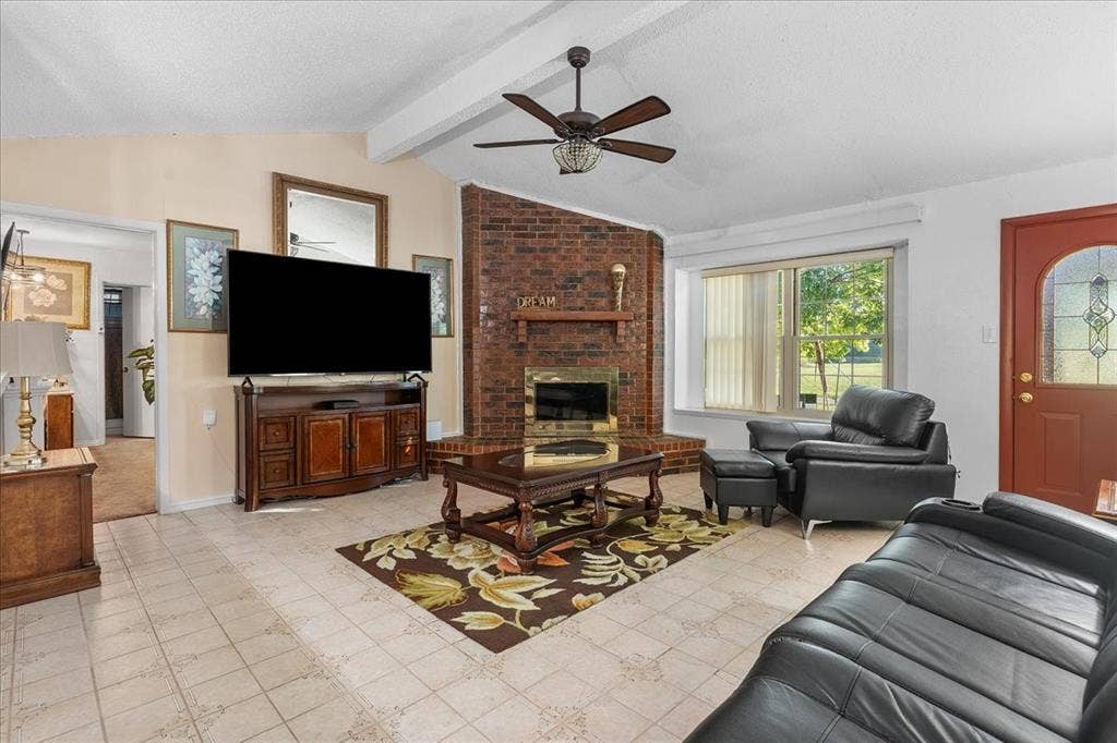 2702 Pebble Beach Drive, Lancaster, TX 75134 Living area featuring vaulted ceilings, floor-to-ceiling brick fireplace with wood mantel, tile flooring, and multi-pane entry door