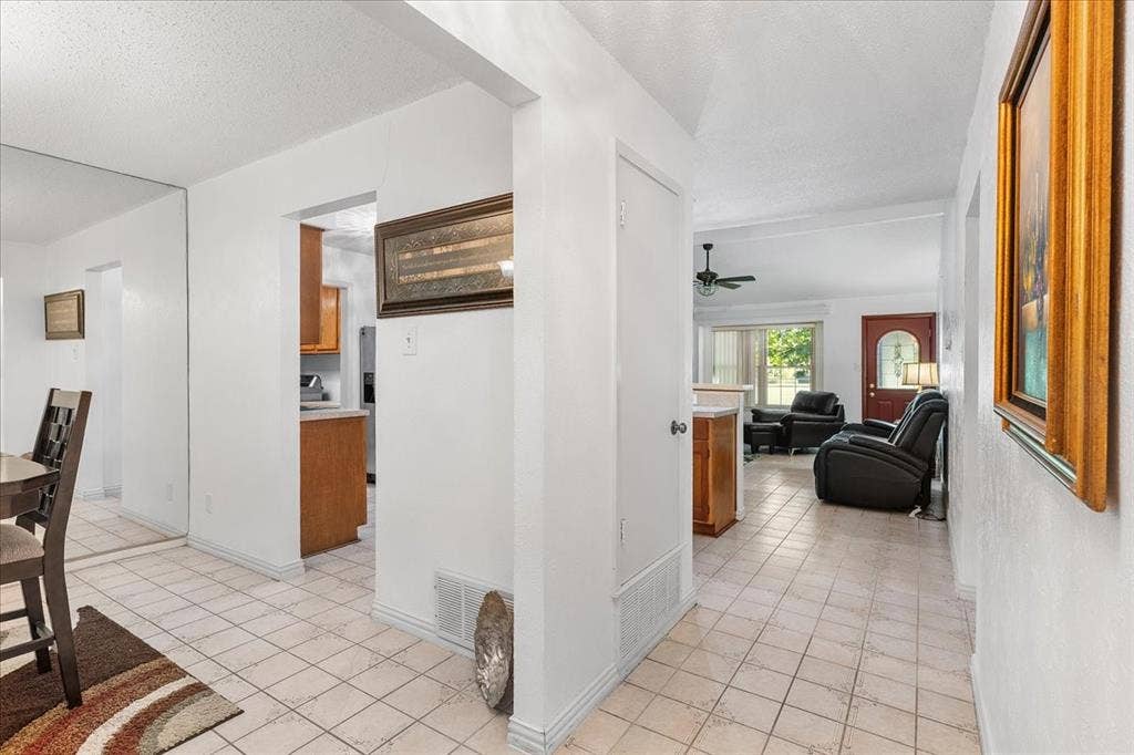 2702 Pebble Beach Drive, Lancaster, TX 75134 Interior space featuring light-colored tile flooring, full-wall mirrored paneling, and an entry door with glass detailing