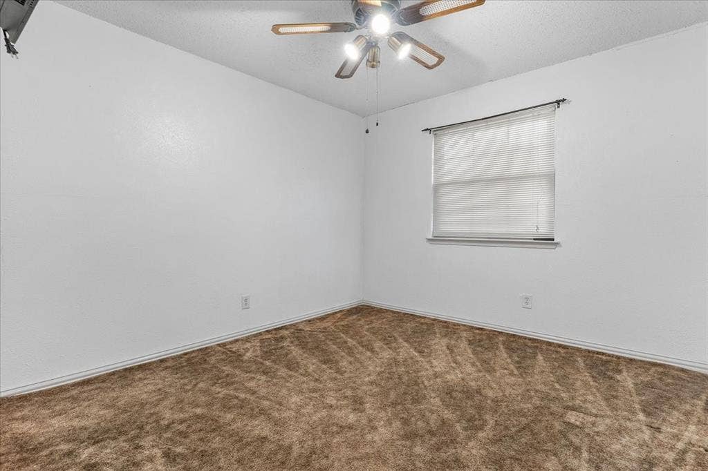 2702 Pebble Beach Drive, Lancaster, TX 75134 Neutral-toned carpeting, textured ceiling, ceiling fan with integrated lighting, and a single-pane window with horizontal blinds