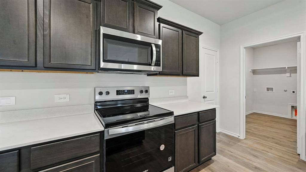 2620 Ocean View Grove, Crandall, TX 75114 Kitchen workspace featuring dark cabinetry, white countertops, stainless steel appliances, and a smooth-top range
