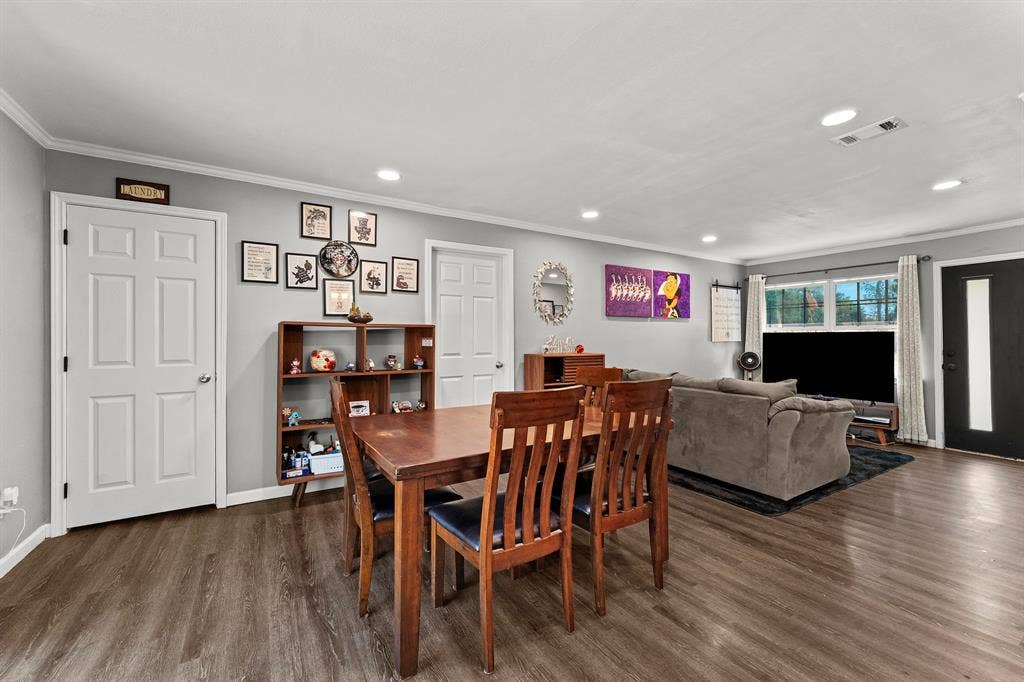 Open-concept interior featuring wood-finish flooring, recessed lighting, neutral wall paint, and an exterior door with a decorative glass panel