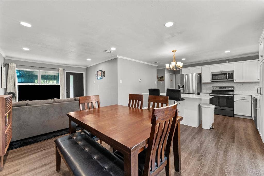 Kitchen featuring white cabinetry, an island with stone-composite countertop, and wood-finish flooring throughout
