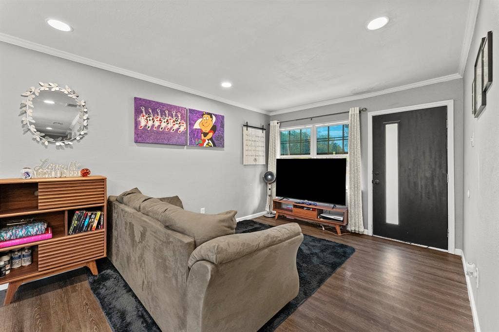 Living area featuring wood-finish flooring, recessed lighting, and a modern entry door with a vertical glass panel