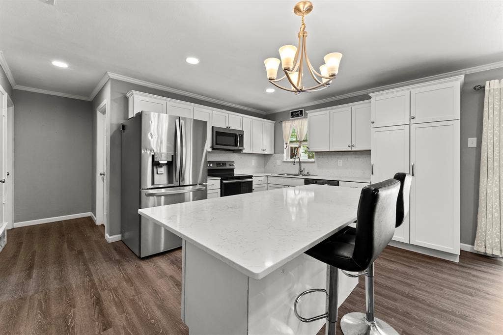 Kitchen featuring white cabinetry, quartz countertops, a central island, stainless steel appliances, and wood-finish flooring