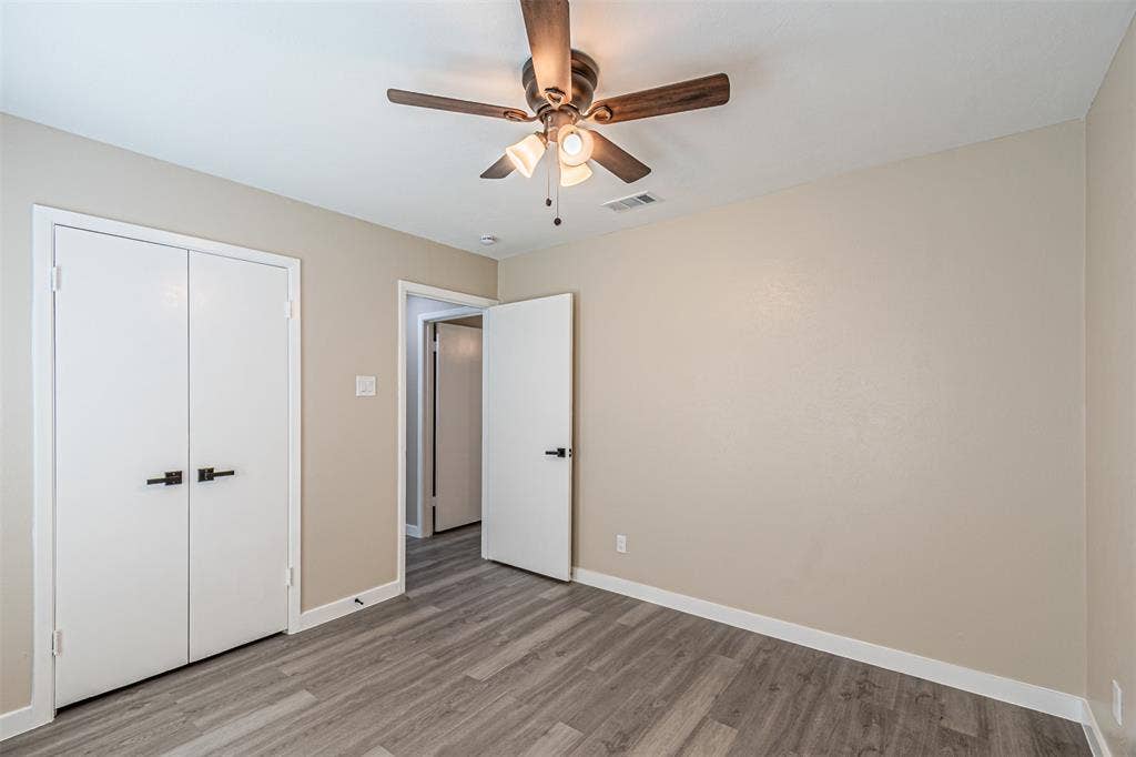 1509 Crockett Street, Garland, TX 75042 Wood-finish flooring, ceiling fan with integrated lighting, and white interior doors featuring matte black hardware