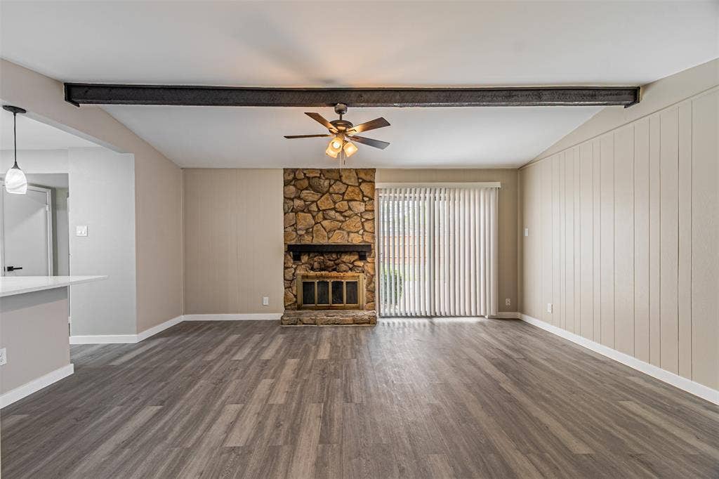 1509 Crockett Street, Garland, TX 75042 Living area featuring a natural stone fireplace, exposed structural steel beam, wood-finish flooring, and sliding glass doors