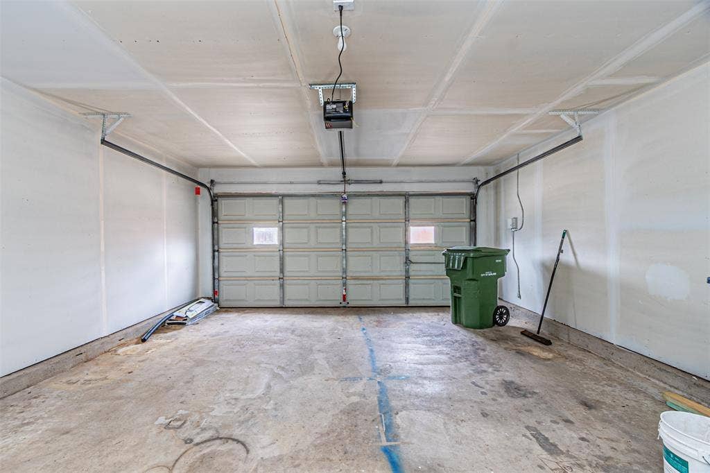 1509 Crockett Street, Garland, TX 75042 Two-car garage featuring a sectional metal door with inset windows, concrete flooring, and an automated overhead door opener