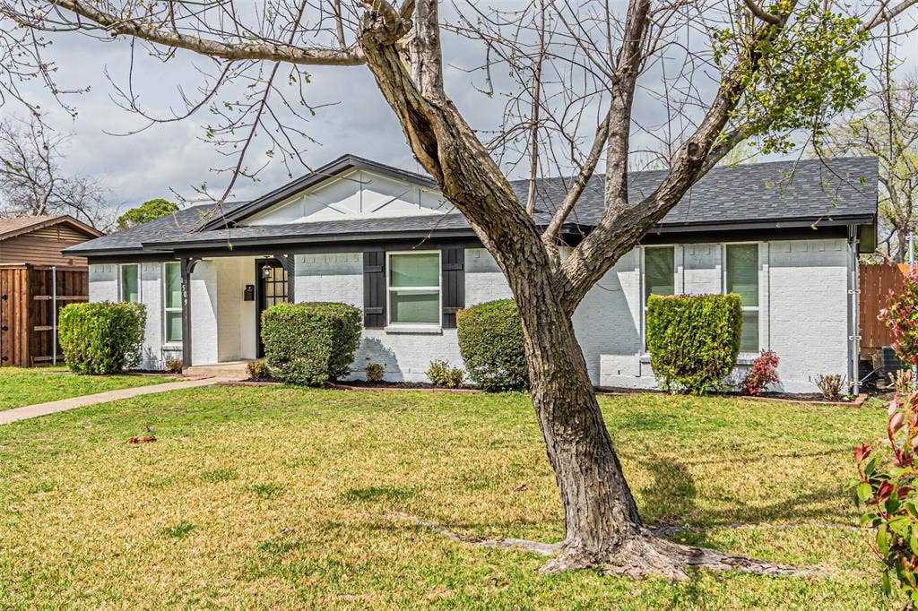 1509 Crockett Street, Garland, TX 75042 Single-story residence featuring a painted masonry exterior, gable roofline, decorative timber-frame accents, and dark shutters