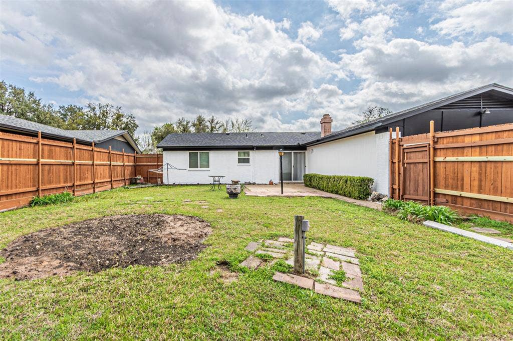 1509 Crockett Street, Garland, TX 75042 Backyard featuring a privacy wood fence, stone patio, and exterior brick finish