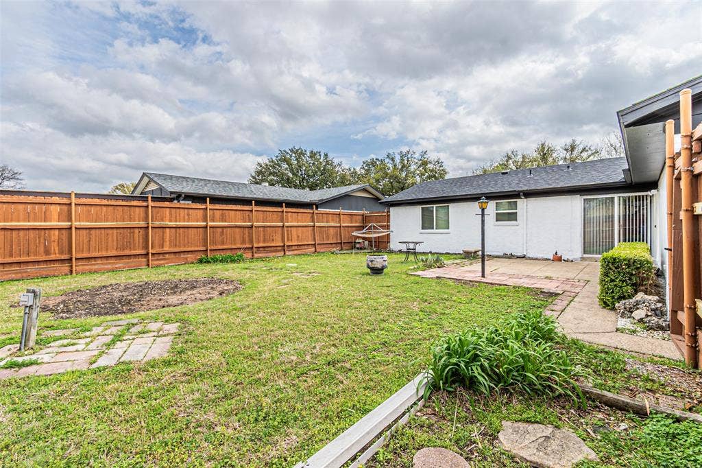 1509 Crockett Street, Garland, TX 75042 Backyard featuring a privacy wood fence, concrete patio, and sodded lawn