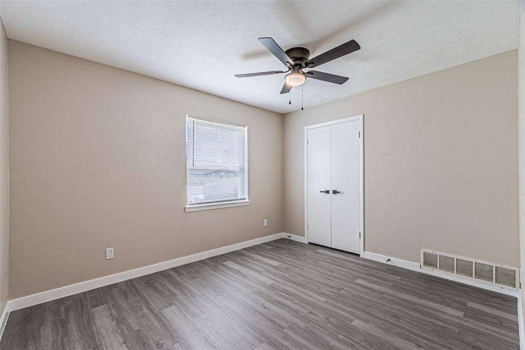 1509 Crockett Street, Garland, TX 75042 Neutral wall finishes, wood-finish flooring, ceiling-mounted light fixture with fan, and double-door closet