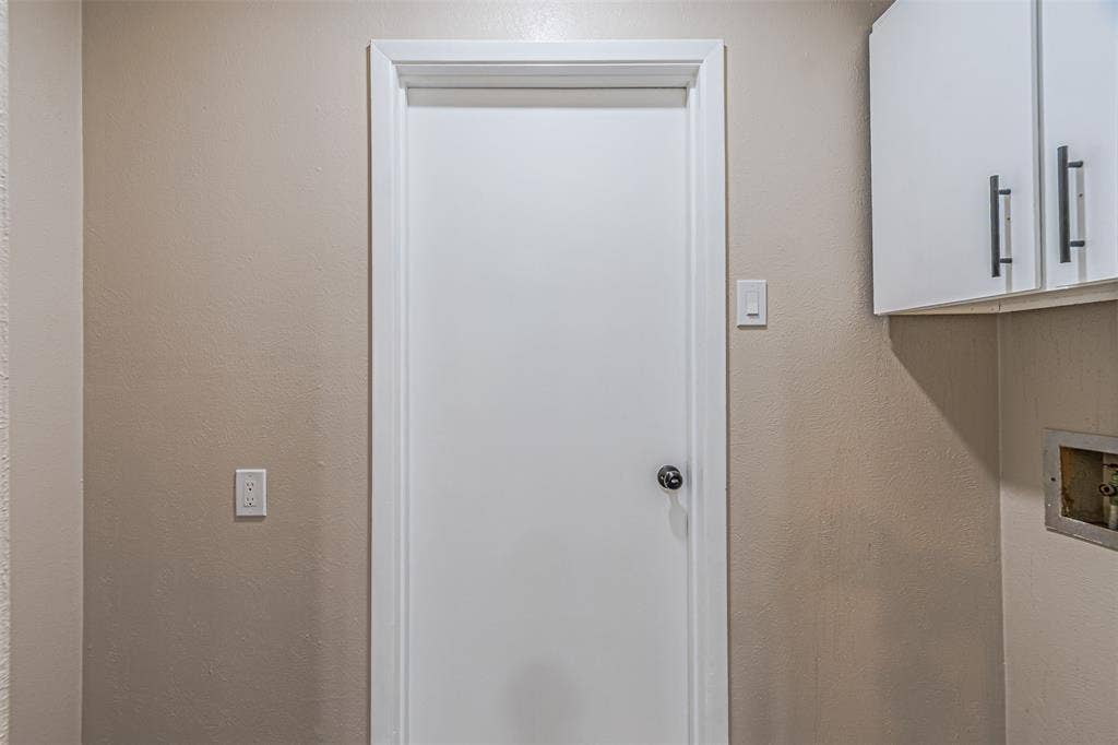 1509 Crockett Street, Garland, TX 75042 Interior door featuring a crisp white finish with a circular knob, paired with white upper cabinetry and brushed metal hardware