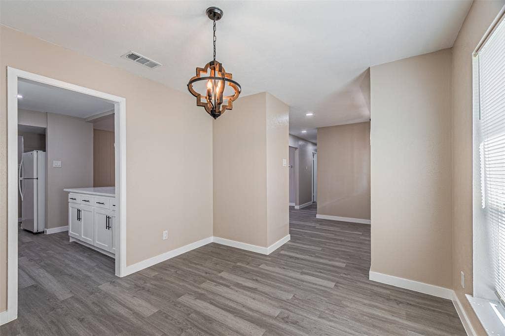 1509 Crockett Street, Garland, TX 75042 Wood-finish flooring, neutral wall tones, and a multi-light spherical chandelier featuring an open-frame metal and wood design