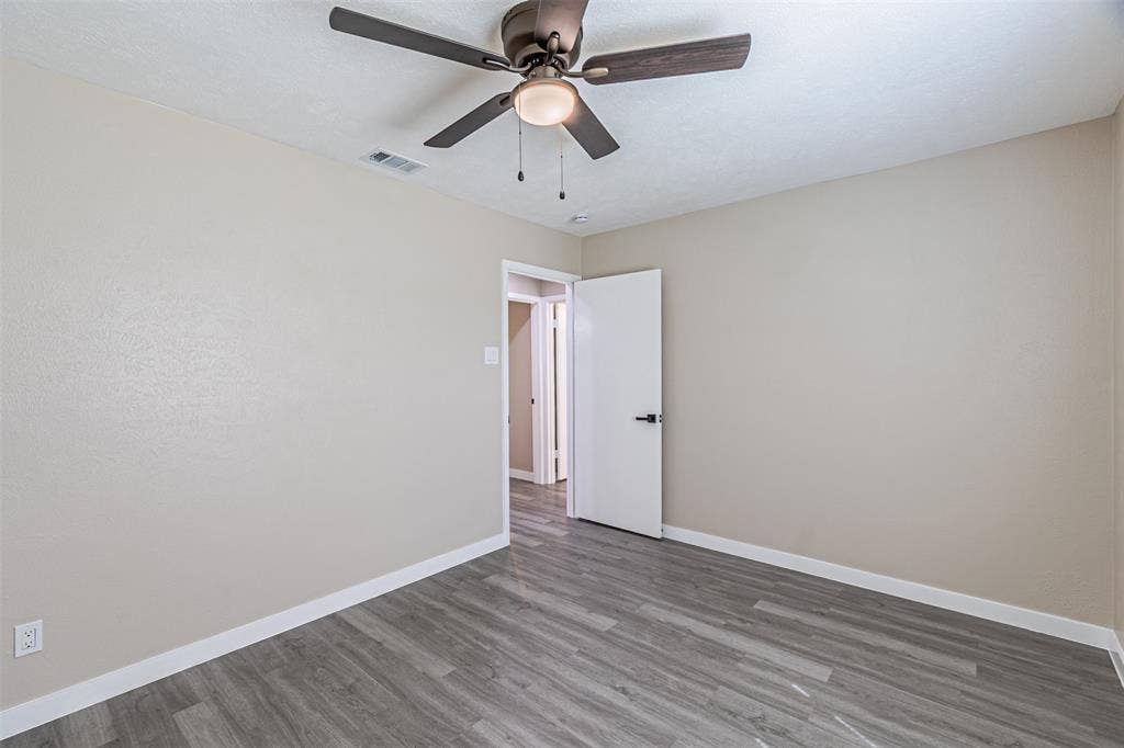 1509 Crockett Street, Garland, TX 75042 Room featuring wood-finish flooring, a ceiling fan with integrated lighting, and a white interior door with matte black hardware