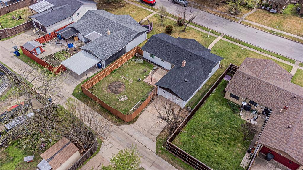 1509 Crockett Street, Garland, TX 75042 Aerial view of a residential lot featuring a concrete driveway, a fenced backyard, and a shingled roof