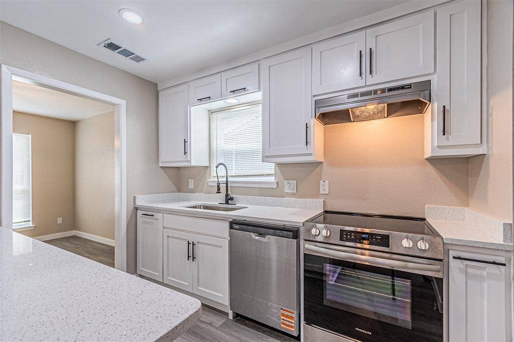 1509 Crockett Street, Garland, TX 75042 Kitchen featuring white shaker-style cabinetry, quartz countertops, stainless steel appliances, and a matte black gooseneck faucet