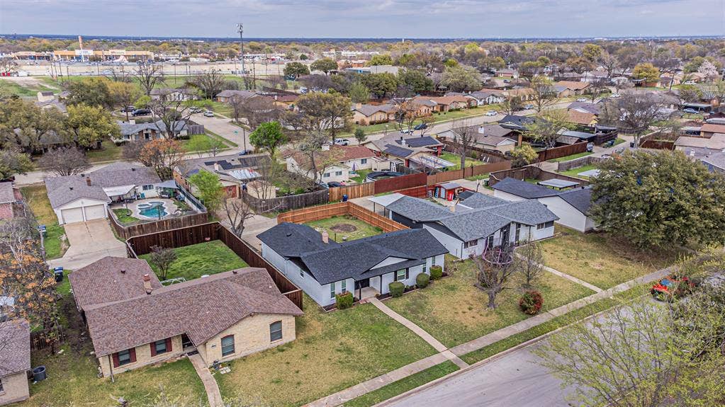 1509 Crockett Street, Garland, TX 75042 Aerial perspective featuring a single-story residence with a dark shingled roof, a fenced backyard, and established mature trees situated within a residential neighborhood