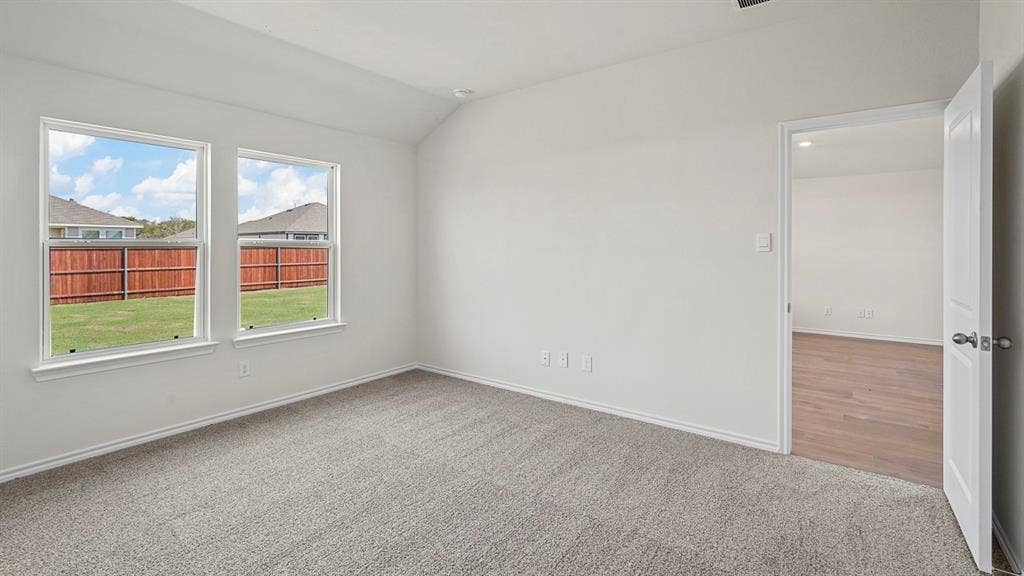 235 Whispering Pine Drive, Royse City, TX 75189 Vaulted ceiling featuring neutral wall-to-wall carpeting, dual windows, and a doorway revealing wood-finish flooring