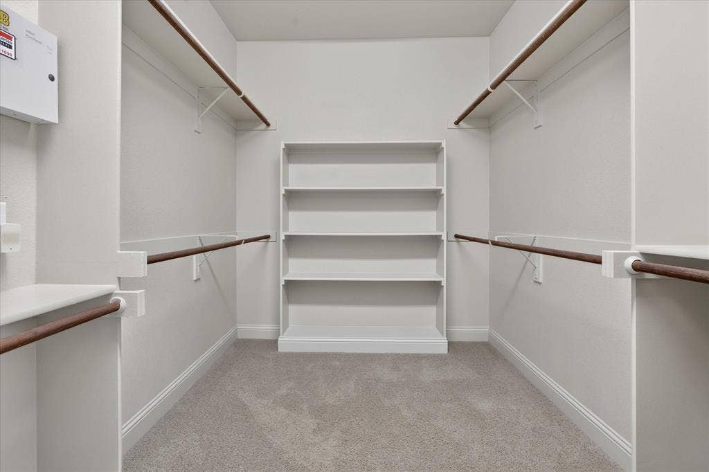 563 Rockingham Drive, Irving, TX 75063 Walk-in closet featuring wall-to-wall carpeting, tiered built-in shelving, and dual-level hanging rods