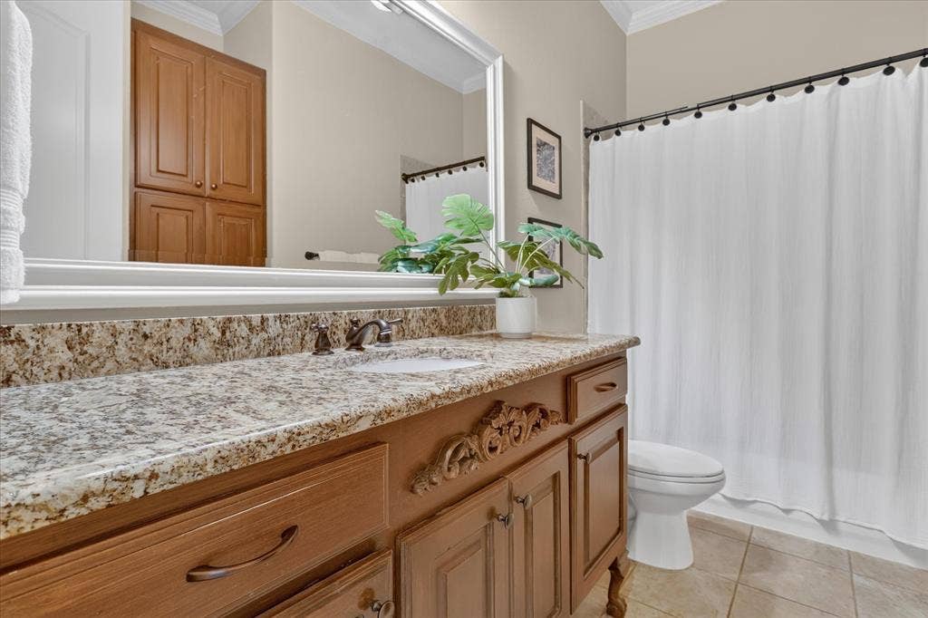 563 Rockingham Drive, Irving, TX 75063 Bathroom featuring a stone-topped vanity with decorative wood cabinetry, large wall-mounted mirror, ceramic tile flooring, and a shower-tub combination