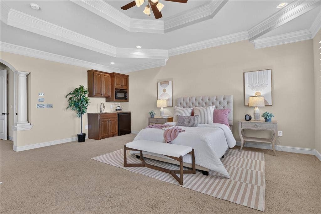 563 Rockingham Drive, Irving, TX 75063 Tray ceiling with crown molding, built-in wet bar with cabinetry and integrated microwave, decorative architectural pillar, and recessed lighting