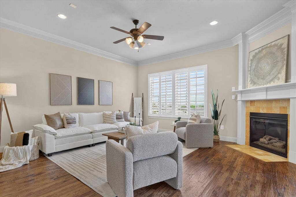 563 Rockingham Drive, Irving, TX 75063 Living area featuring wood-finish flooring, crown molding, a fireplace with a stone-surround hearth, and plantation shutters