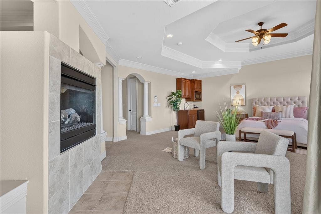 563 Rockingham Drive, Irving, TX 75063 Tray ceiling with recessed lighting, fireplace with stone-finish surround, built-in cabinetry with integrated sink, and architectural column detailing