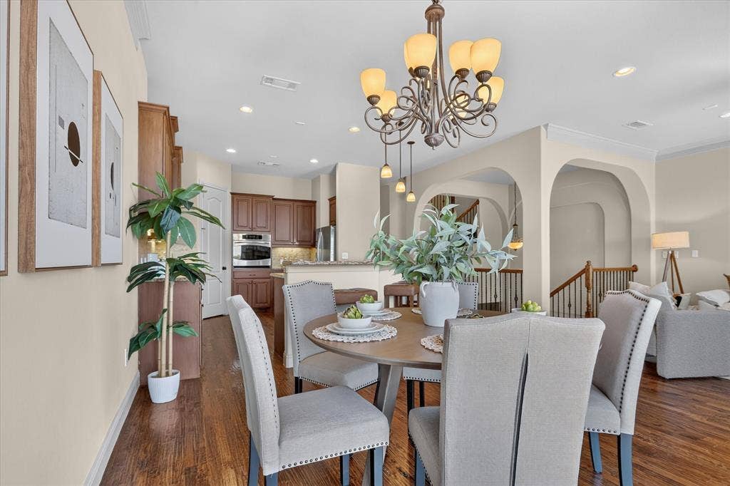 563 Rockingham Drive, Irving, TX 75063 Open-concept dining area featuring dark wood-finish flooring, an ornate multi-light chandelier, arched architectural wall openings, and recessed lighting